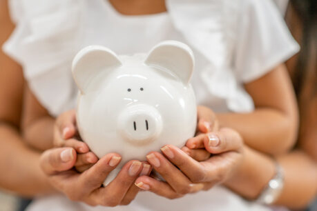 Parent and child holding piggy bank together
