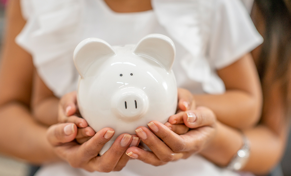 Parent and child holding piggy bank together