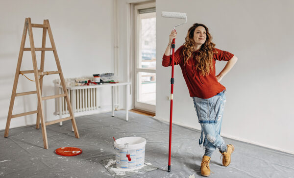 Woman holding paint roller looking proud of freshly painted room