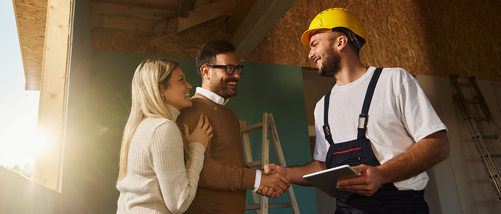 Man and woman smiling and shaking hands with builder