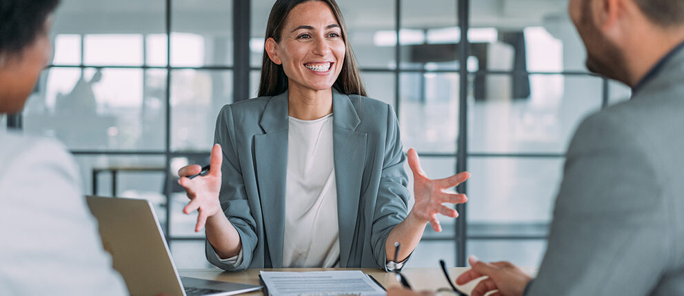 Smiling woman talking to two people sitting across from her