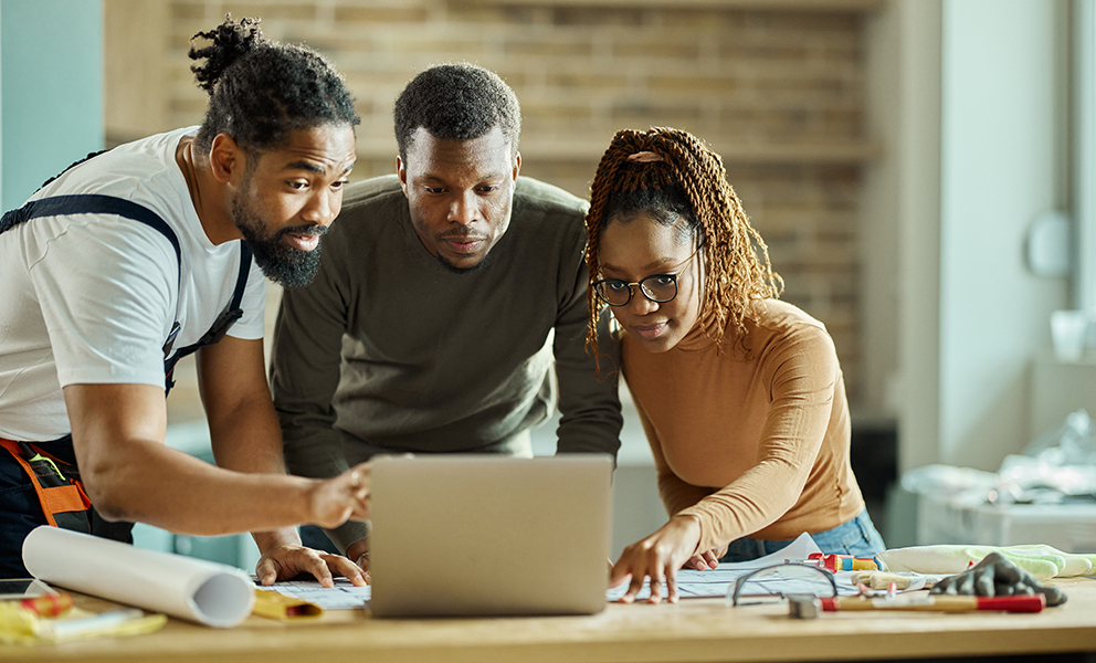 Couple discussing building plans with builder over laptop