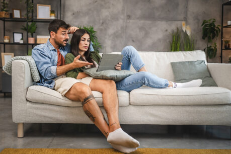 Couple discussing over laptop while sitting together on couch