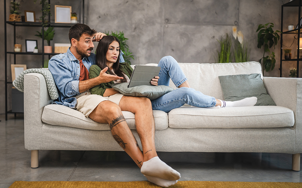 Couple discussing over laptop while sitting together on couch