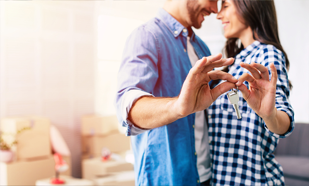 Smiling couple holding keys to new house in brand new living room