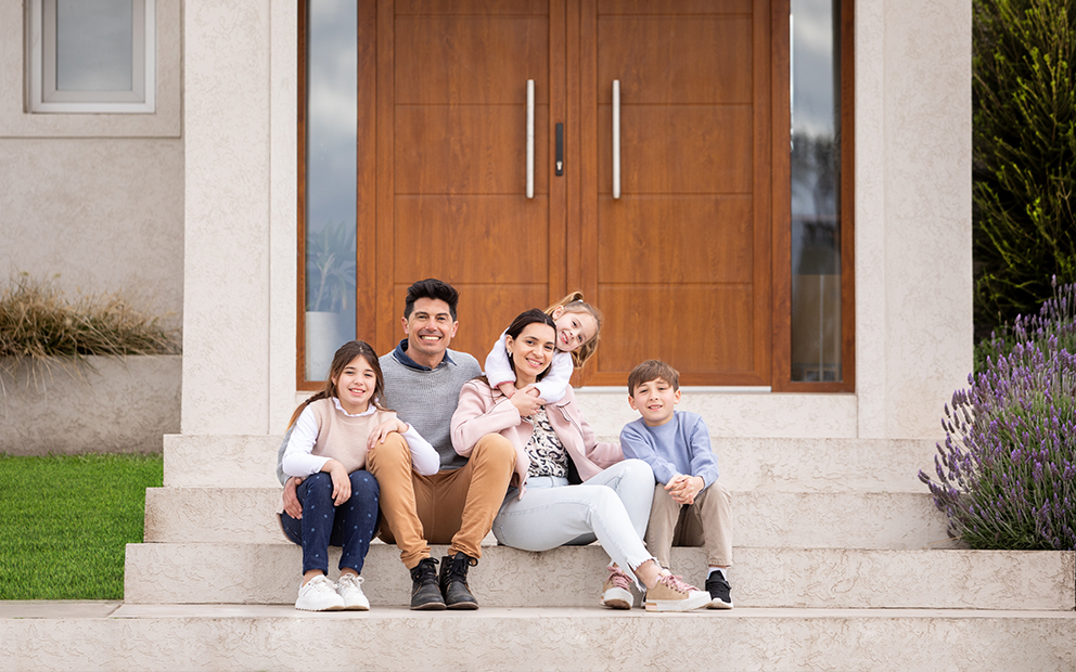 Couple and their children happily sitting on outside of steps of new home