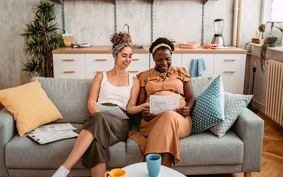 Couple happily reviewing and discussing documents together while sitting on their couch