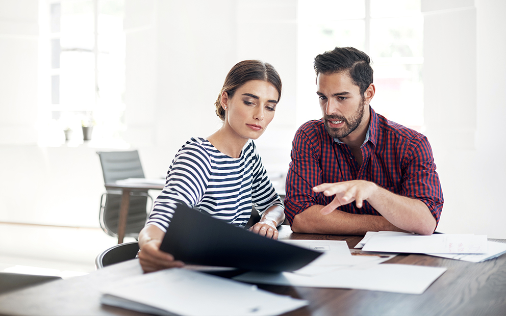 Couple sitting at table together while they talk and look over documents