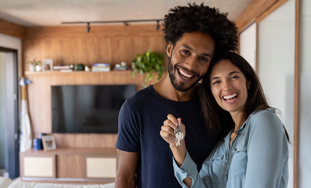 Couple holding keys to new home inside kitchen