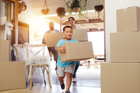 Husband, wife, and their son carrying boxes into new home