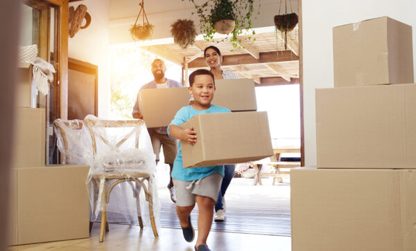 Husband, wife, and their son carrying boxes into new home