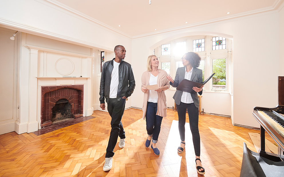 Man and woman couple taking tour of older home with realtor