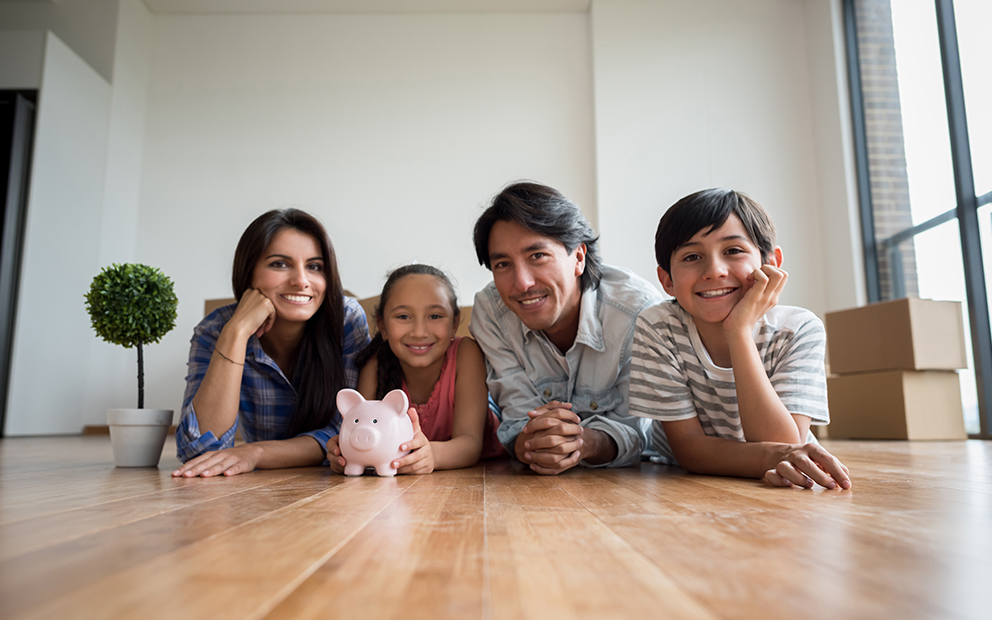 Family smiling while lying down on floor of new home