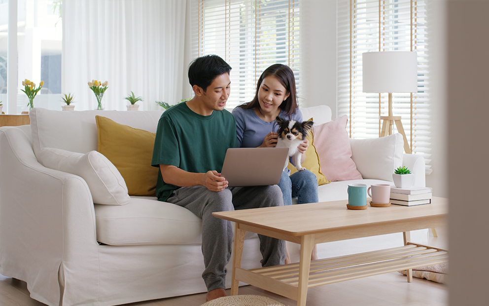 Man and woman couple sitting on couch together while discussing finances on laptop