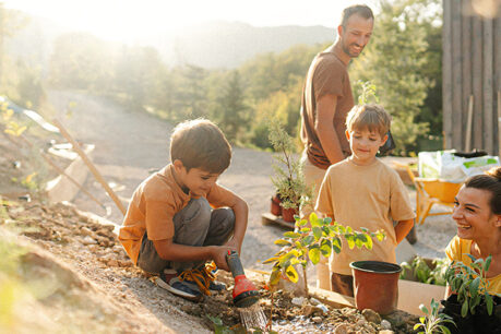 Man and woman couple gardening in yard with their two kids