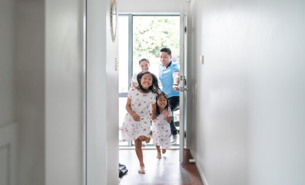 Two sisters running through the doorway of their new home with their mom and dad