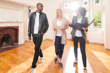 Man and woman couple taking tour of older home with realtor