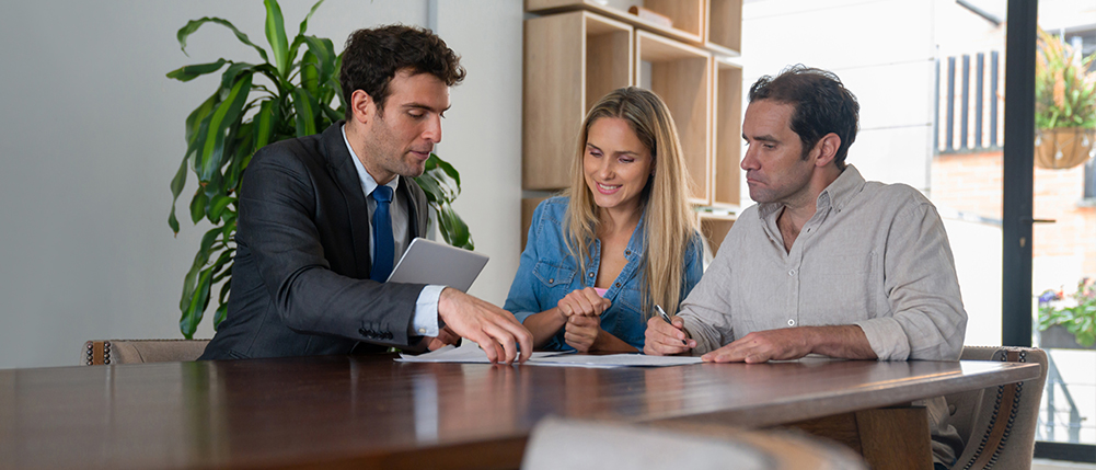 Man and woman couple going over documents with advisor while sitting at a table