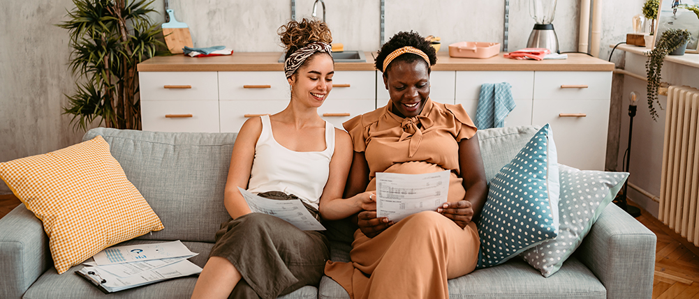 Couple happily reviewing and discussing documents together while sitting on their couch