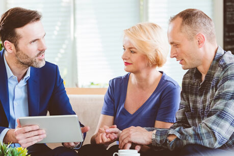 Older man and woman couple going over documents with advisor while sitting at a table