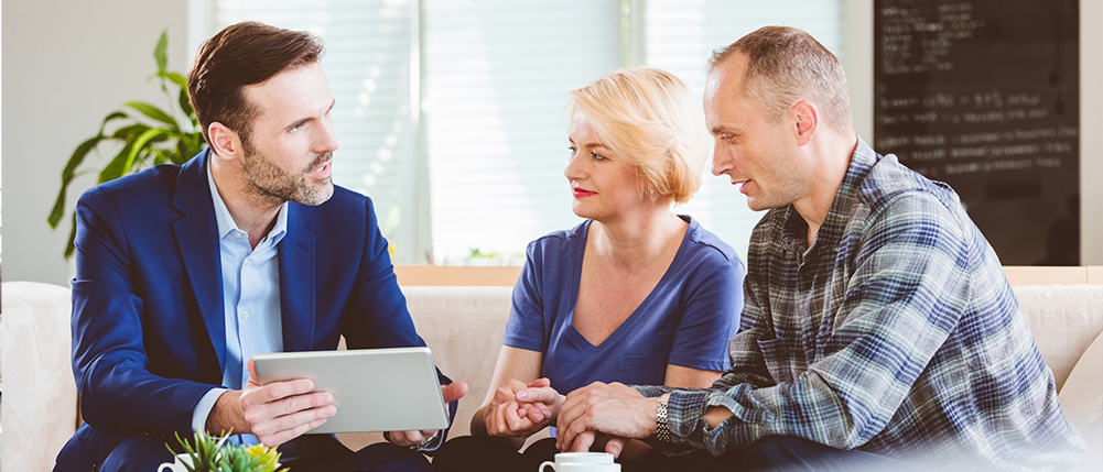 Older man and woman couple going over documents with advisor while sitting at a table