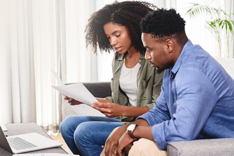 Man and woman sitting on couch while reviewing documents