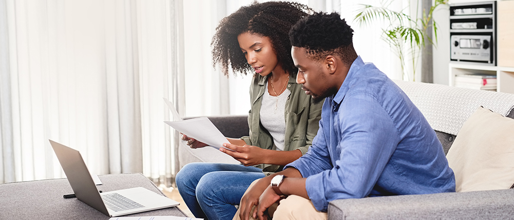 Man and woman sitting on couch while reviewing documents