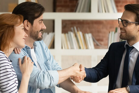 Couple discussing with advisor while smiling and shaking hands