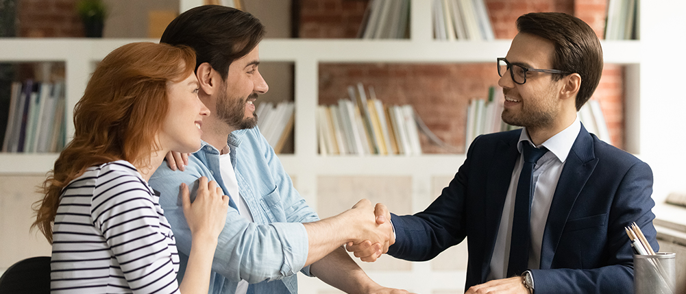 Couple discussing with advisor while smiling and shaking hands