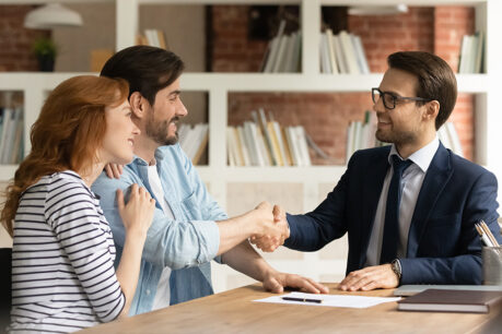 Couple discussing with advisor while smiling and shaking hands