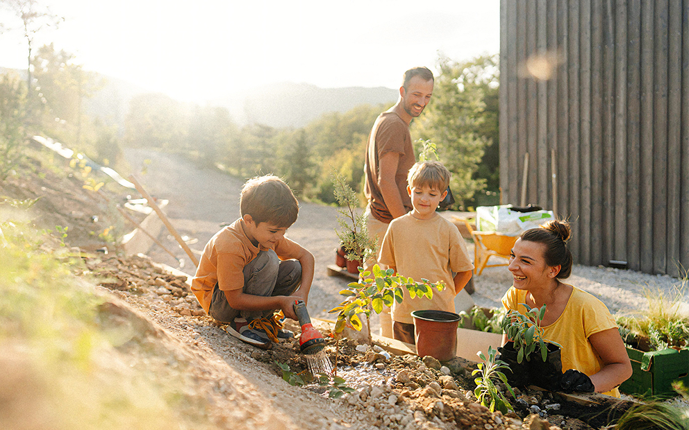 Man and woman couple gardening in yard with their two kids