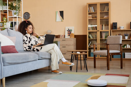 Woman sitting on couch while looking at laptop