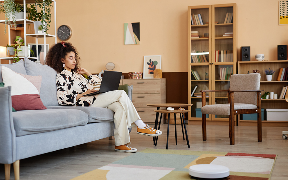 Woman sitting on couch while looking at laptop