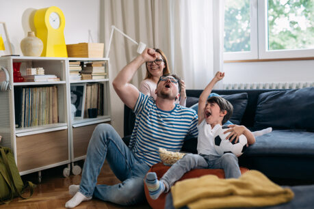 Family sitting on couch while celebrating soccer game