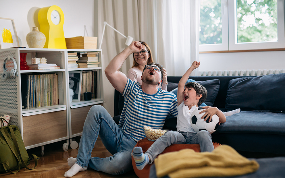 Family sitting on couch while celebrating soccer game