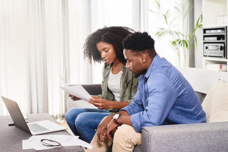 Man and woman sitting on couch while reviewing documents