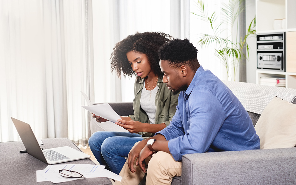 Man and woman sitting on couch while reviewing documents