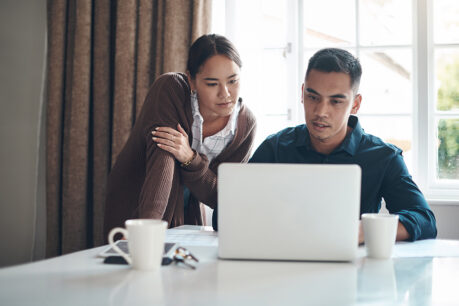 Couple reviewing documents on laptop while sitting at table