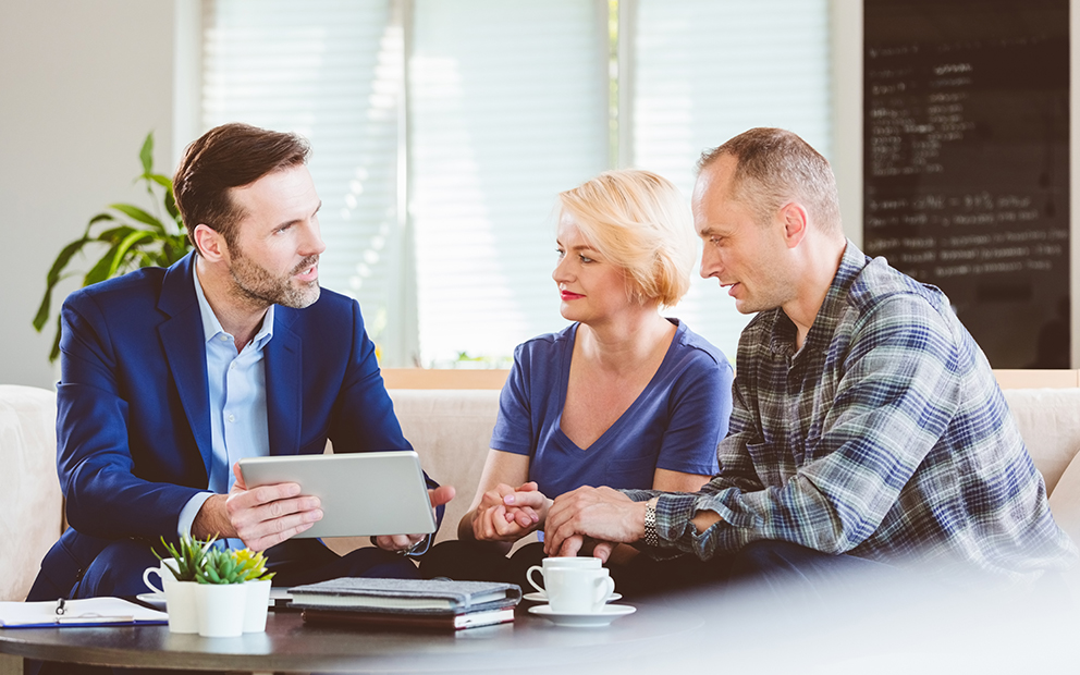 Older man and woman couple going over documents with advisor while sitting at a table