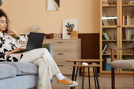 Woman sitting on couch while looking at laptop