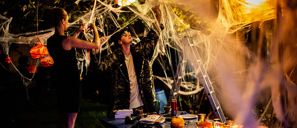 Couple setting up outside of home with Halloween decorations