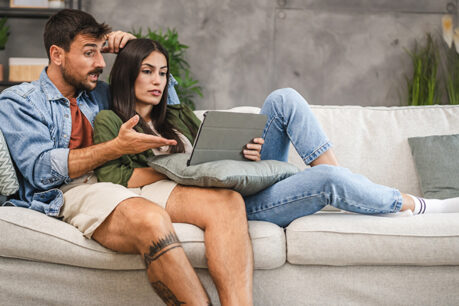 Couple discussing over laptop while sitting together on couch