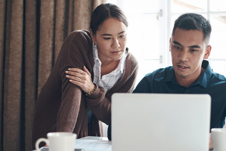 Couple reviewing documents on laptop while sitting at table