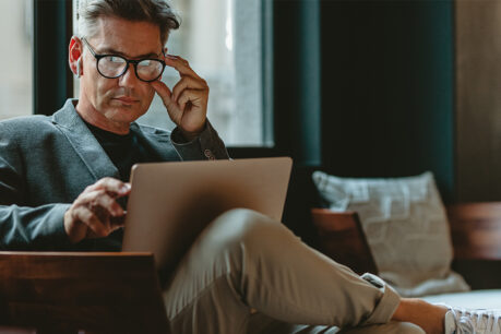 Man examining notes on laptop