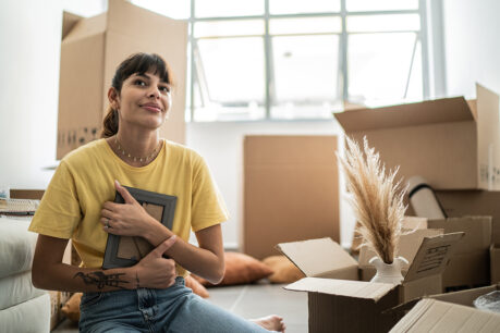 Woman sitting on floor of new home while holding picture frame