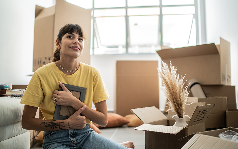 Woman sitting on floor of new home while holding picture frame