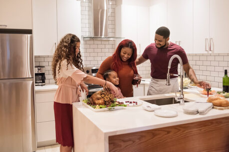 Family of four cooking food together in their home kitchen