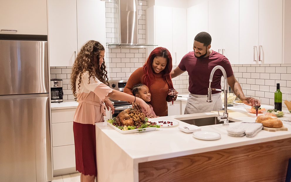 Family of four cooking food together in their home kitchen