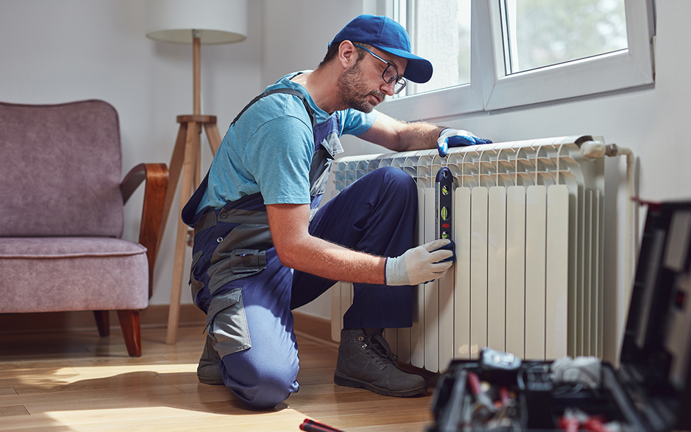 Man working on radiator inside home