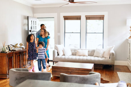 Family of four walking into new home looking happy